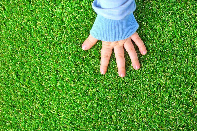 Childs hand resting on artificial grass